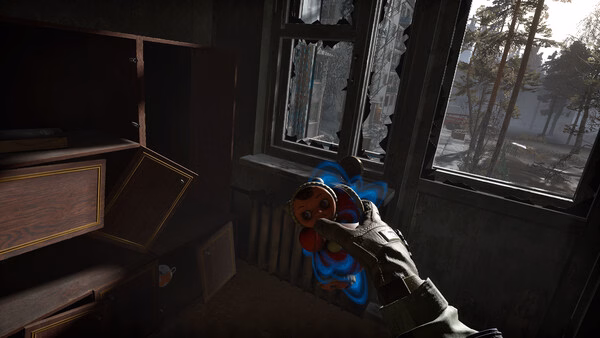 Screenshot from Into the Radius 2 shows a hand holding a doll in a dim room with broken windows and trees visible outside.