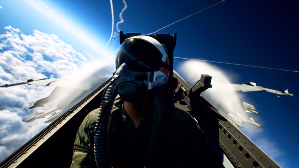 Screenshot from ACE COMBAT 8: WINGS OF THEVE showing a fighter pilot in a cockpit, soaring above clouds with vapor trails in the sky.